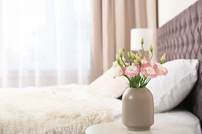 Flowers in a vase by a bed