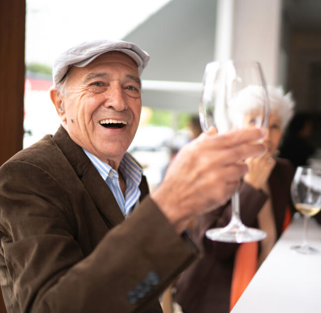 Senior man sitting in a restaurant holding up a wine glass