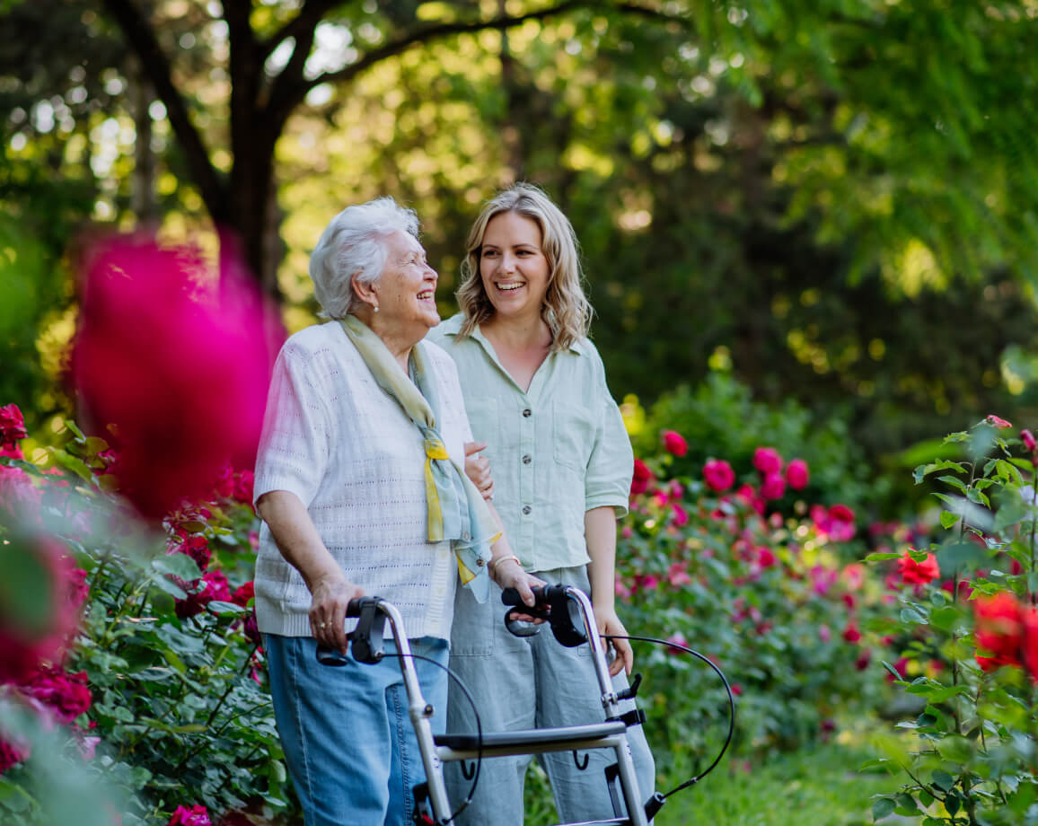 Senior mom using a walker while walking with her adult daughter
