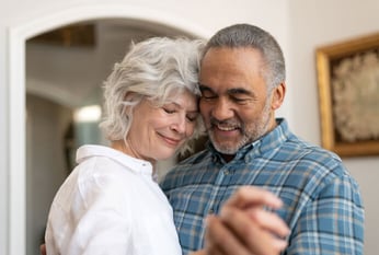 Senior couple slow dancing in living room