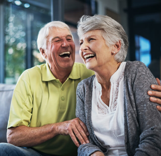 Senior couple sitting on couch smiling