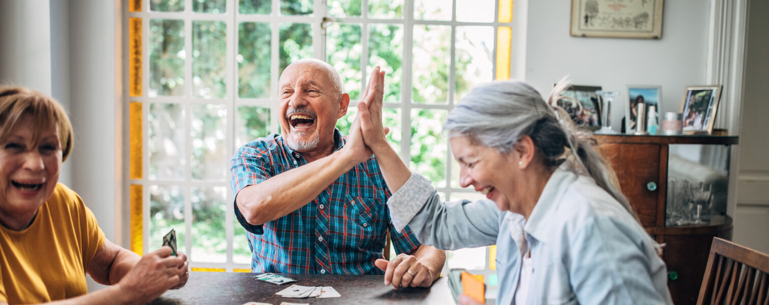 Group of three residents laughing and high-fiving at a table