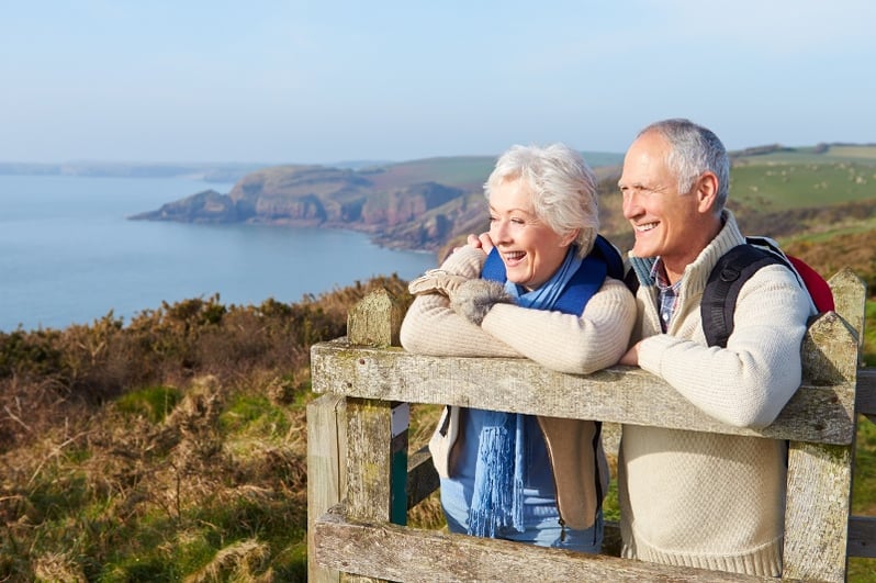 Couple smiling as they lookout at a beautiful landscape. 