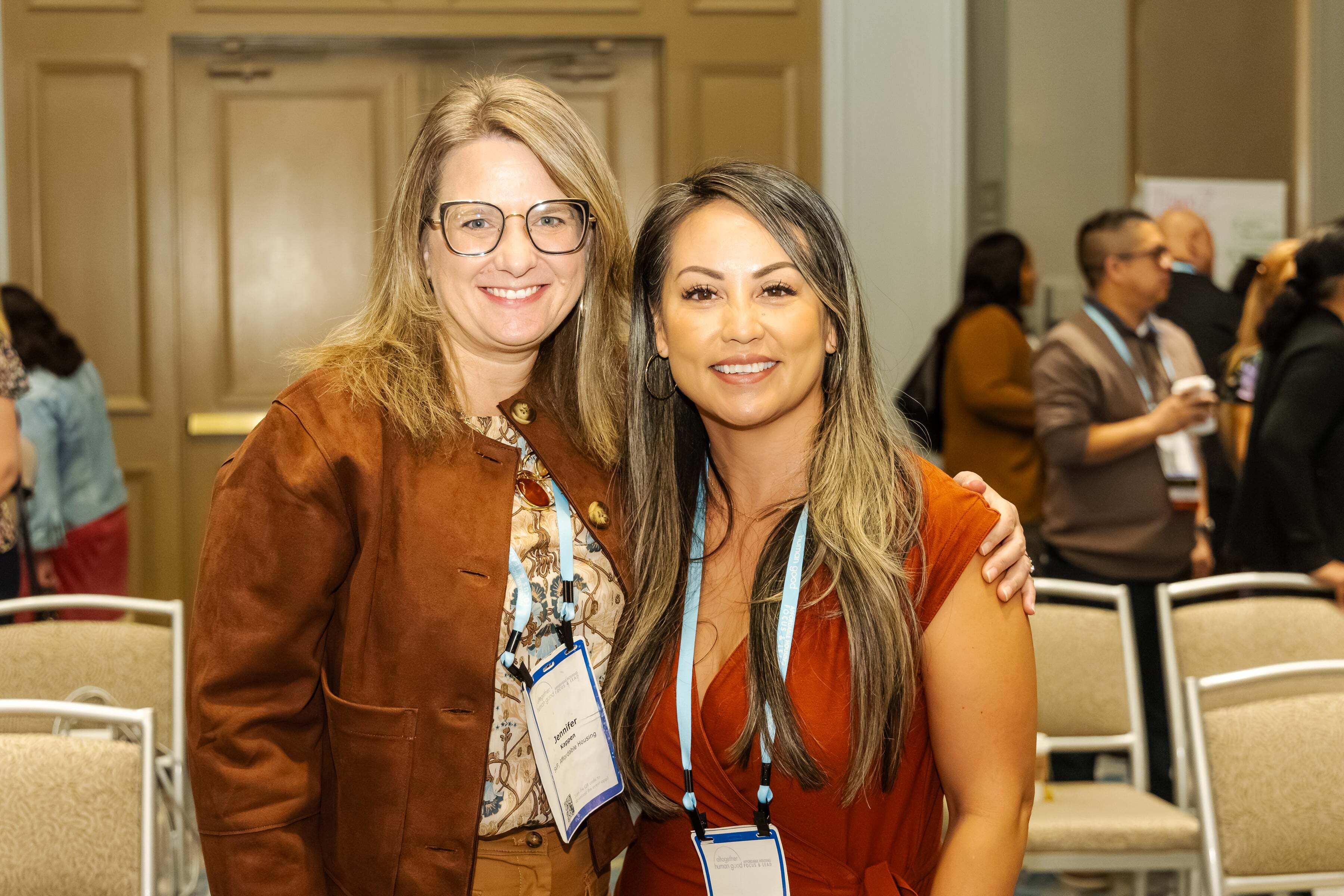 Two HumanGood employees smiling together at a company event, wearing name badges.