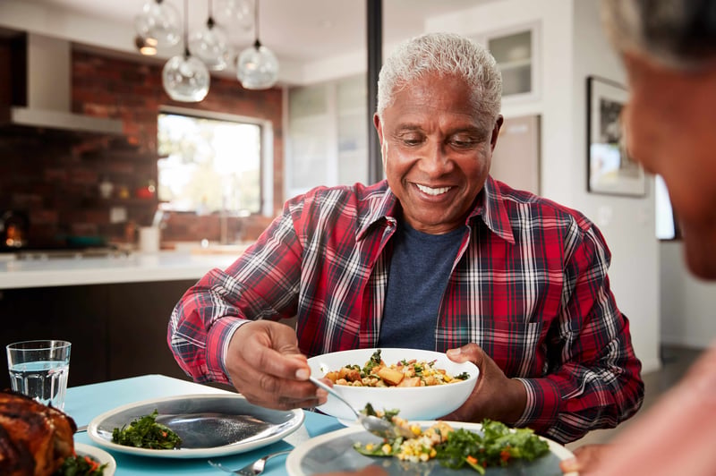 A senior man spends time together with his family at the dinner table while serving a high protein meal