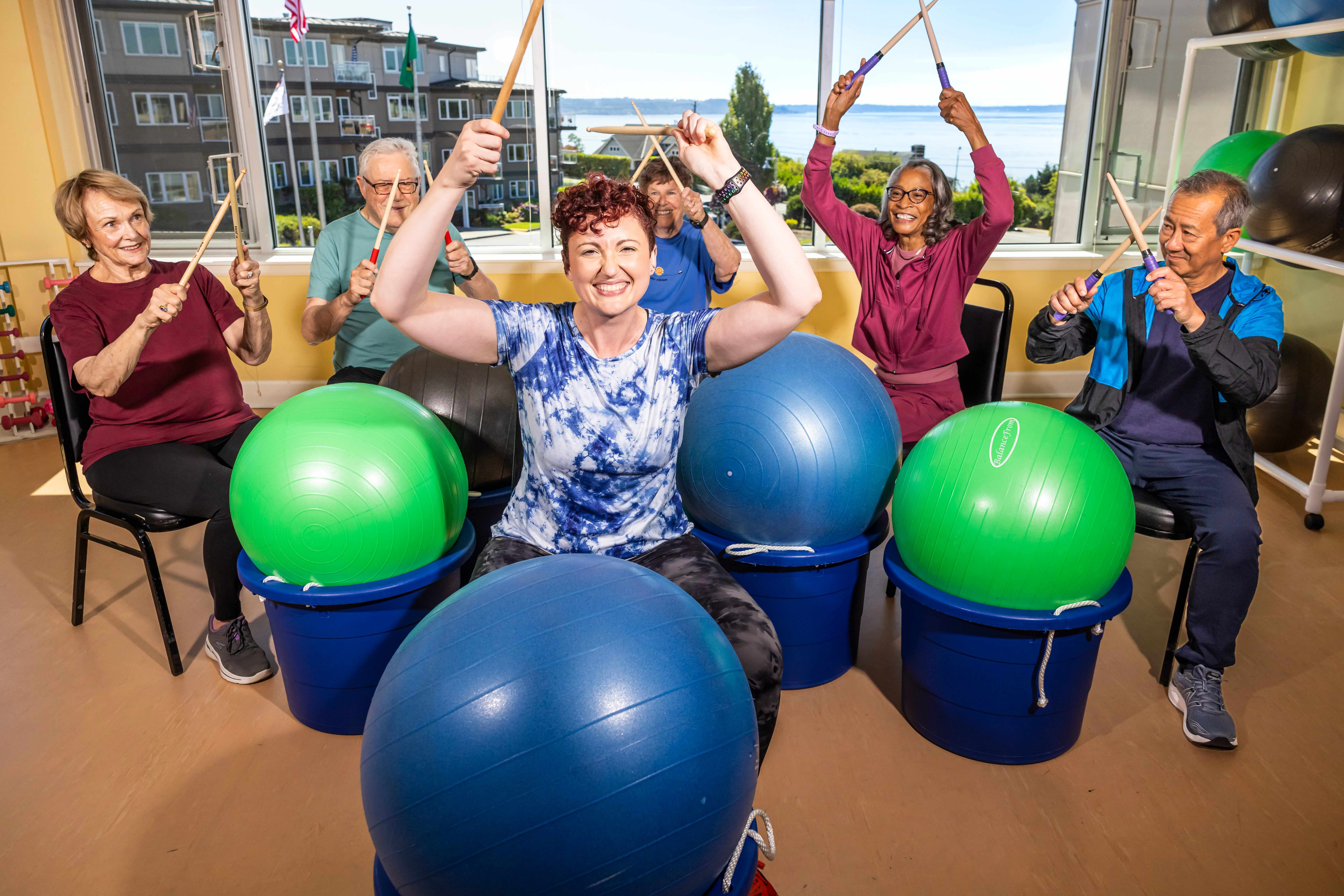 Senior women practicing exercise drumming with an instructor