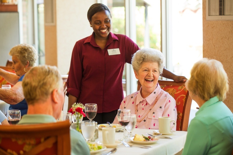 senior friends being greeted by waiter at a restaurant