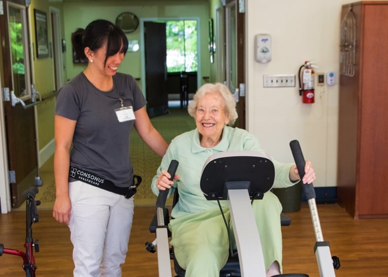 senior woman on fitness equipment with the a help of a professional