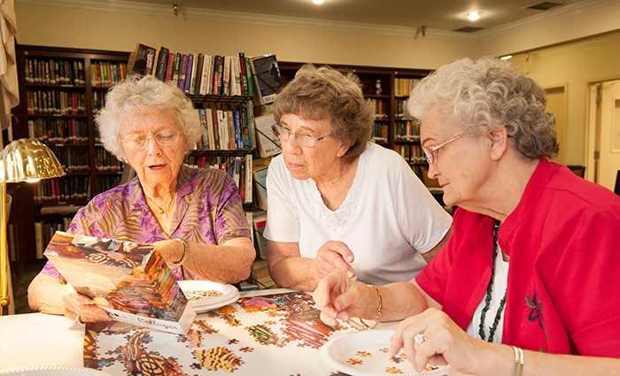 redwood terrace residents enjoy a puzzle in the library