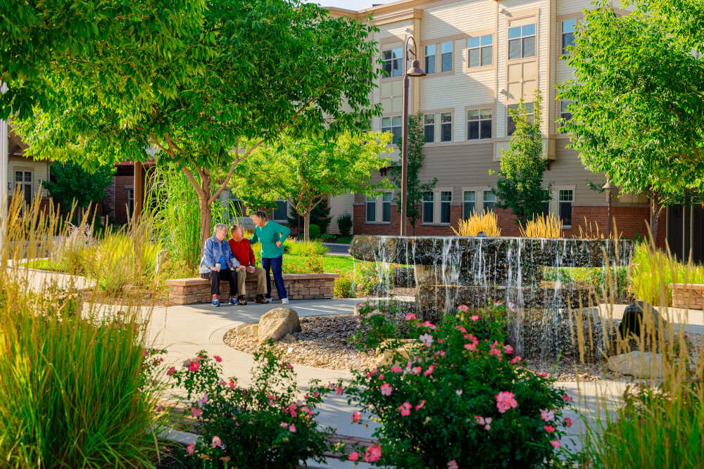 Three people sitting outside by a water fountain