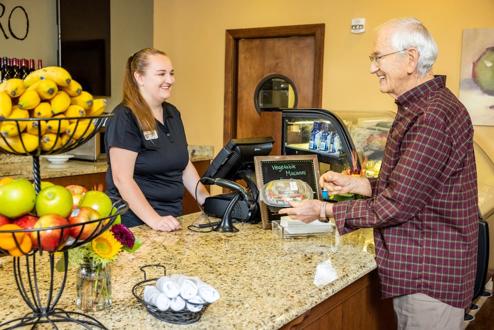 A man purchasing a snack from a woman behind a desk