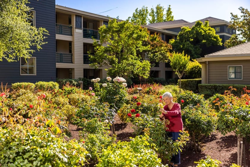 Senior woman looking at flowers in the garden of The Terraces of Los Gatos