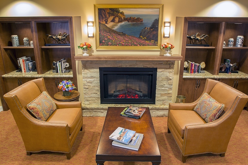 Common living room area with books near a fireplace at senior living community The Terraces at Los Altos in the California Bay Area