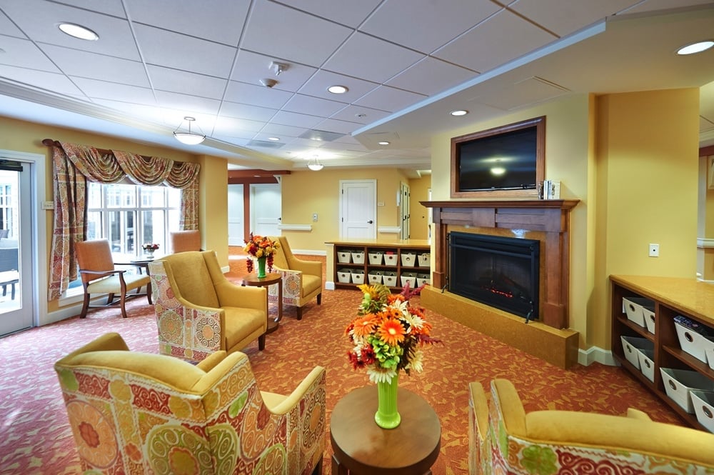 Common living room area with a chimney and television at senior living community The Terraces at Los Altos