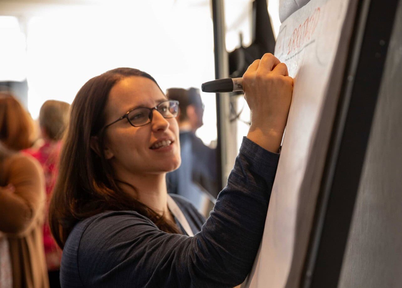 Woman writing on large sheet of paper on easel