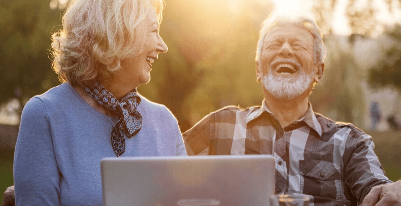 Senior couple laughing while looking at laptop