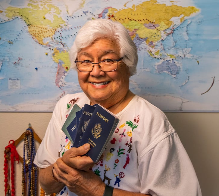 Janet holding passports while sitting in front of a map