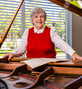 Linda posing next to piano