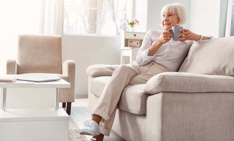 Woman sitting on a couch drinking a cup of coffee