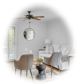 Living room with two chairs, a couch, mirror on the wall and a ceiling fan