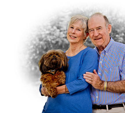 Senior man with his arm around a senior woman who is holding a small brown dog