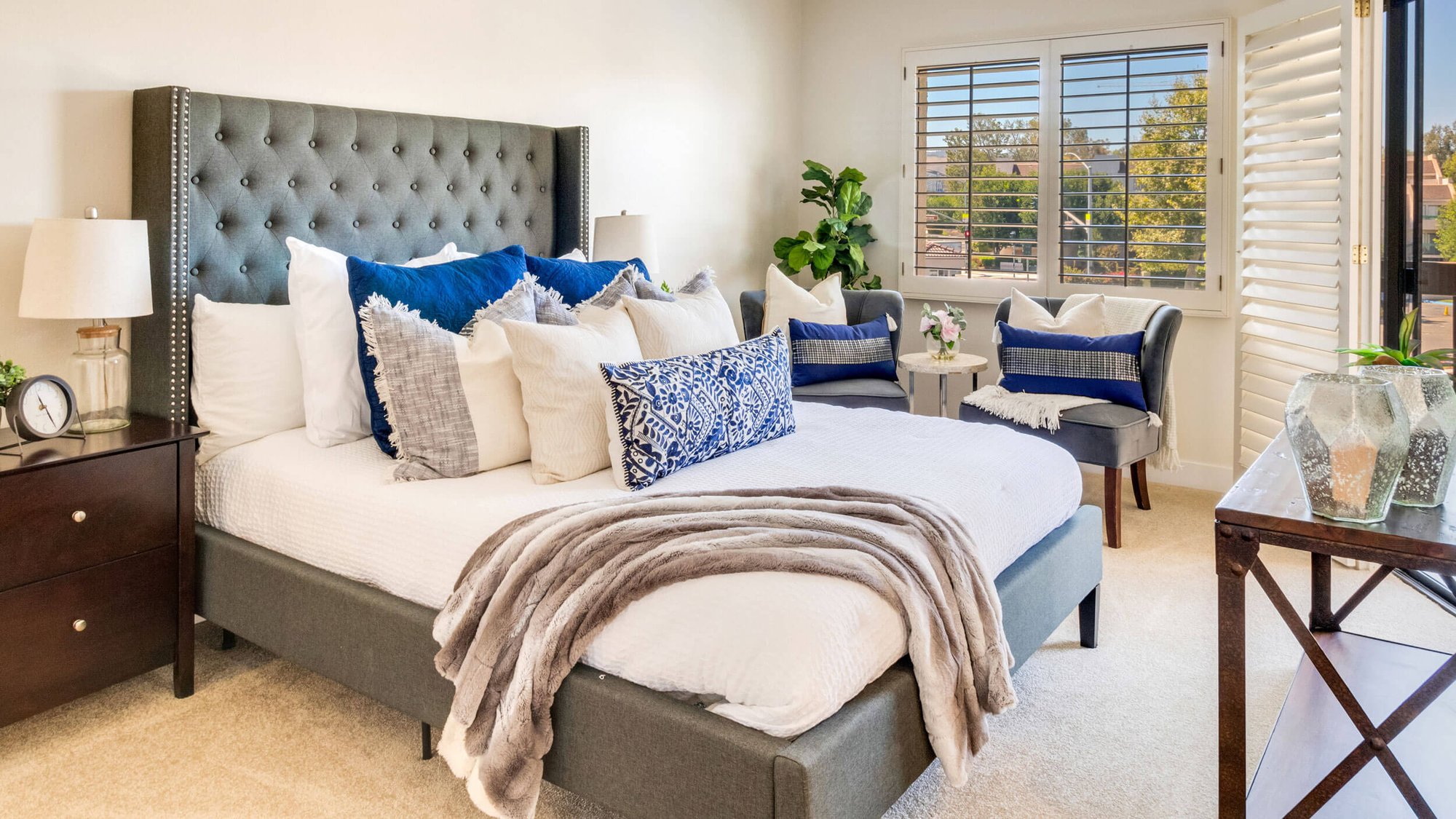 Bedroom with dark gray tufted headboard and dark wood accent furniture in an independent living model home