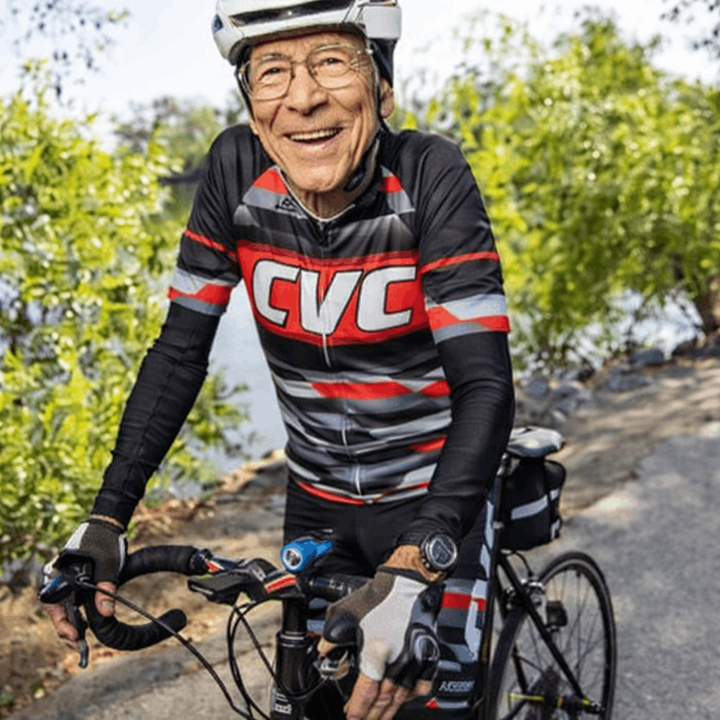 Smiling resident named Louis riding a bicycle outdoors, wearing a helmet and cycling gear.