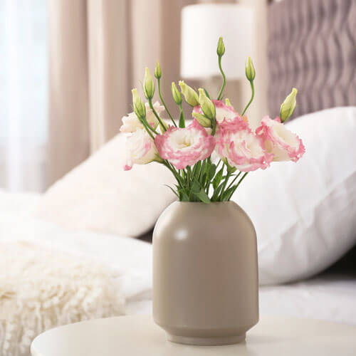 pink flower arrangement in a vase sitting on night stand