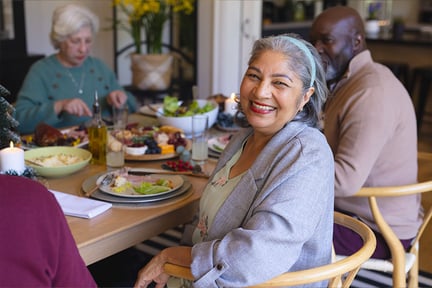 Smiling senior woman sitting at dining table with friends