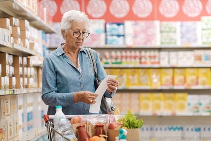 Senior woman looking at her receipt in the aisle of a grocery store