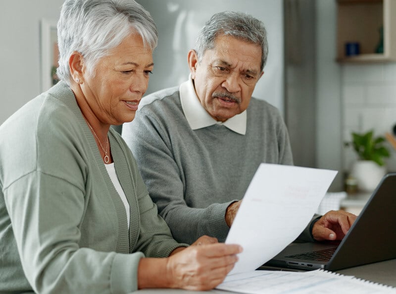 Senior man and woman sitting at a table looking at financial statements