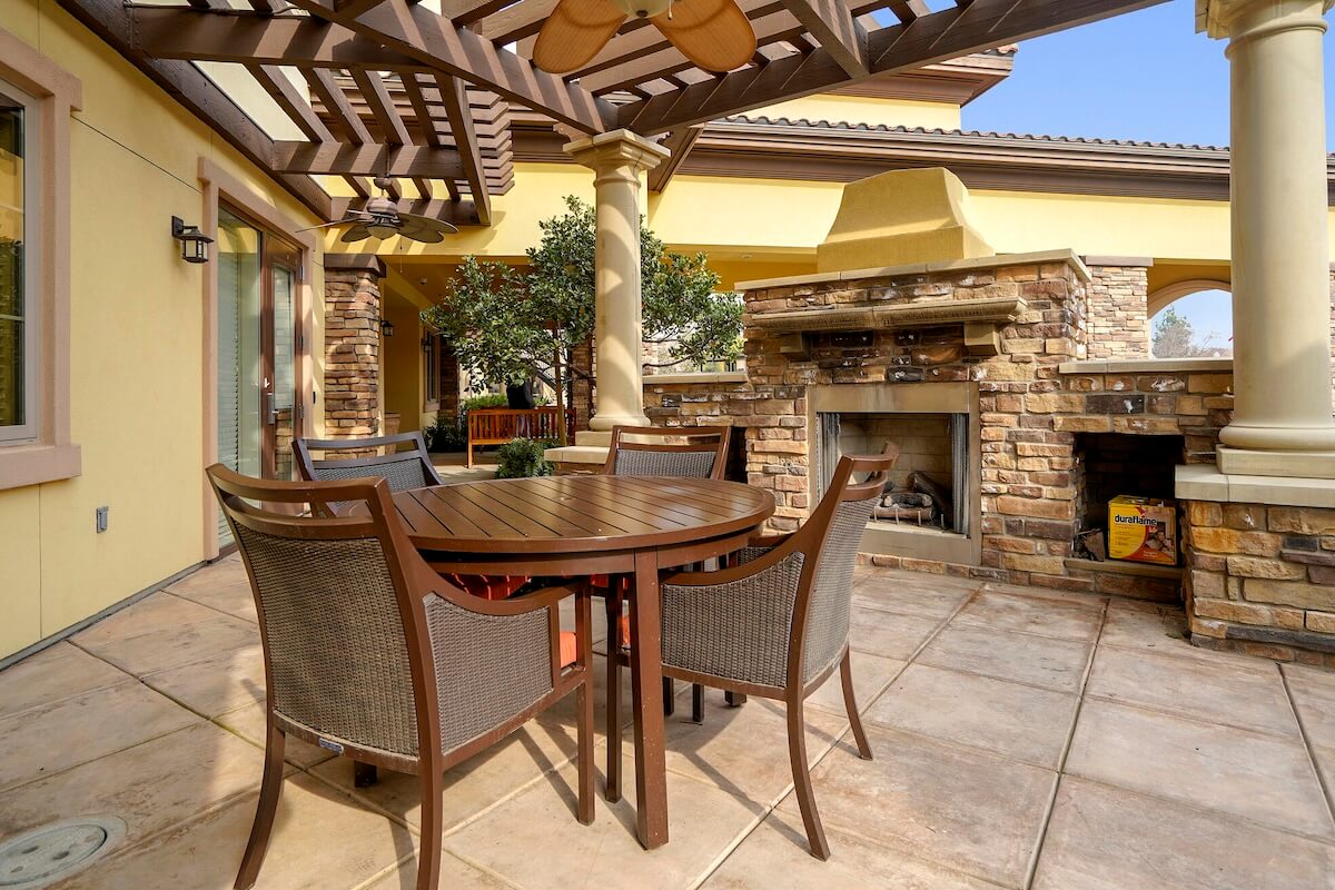 Covered patio with dining table and outdoor fireplace at The Terraces at San Joaquin Gardens