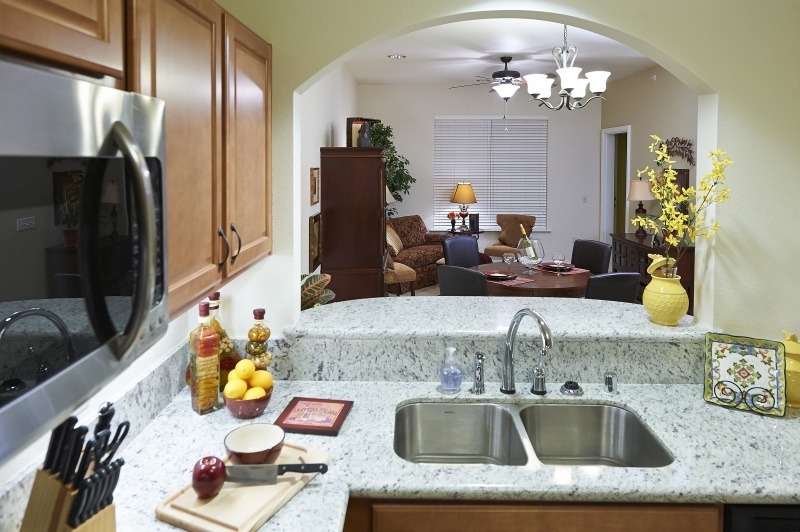 View through a kitchen pass-through to a living room in an apartment at The Terraces at San Joaquin Gardens