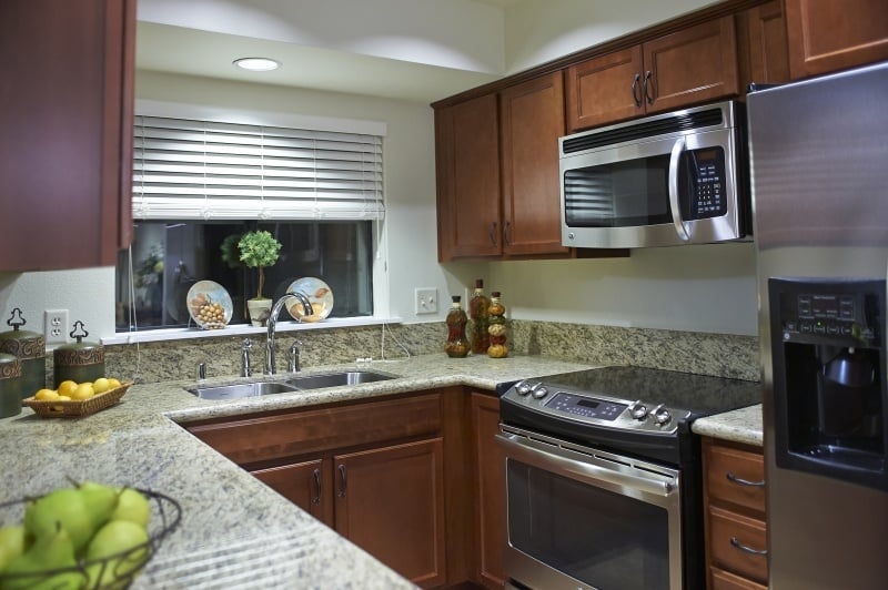 Kitchen with dark wood cabinets and stainless steel appliances in an apartment at The Terraces at San Joaquin Gardens