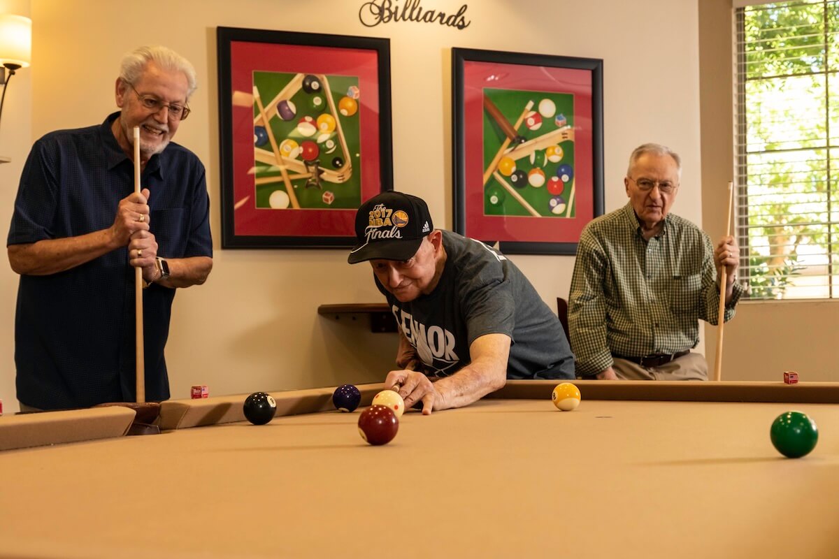 Three senior men playing a game of pool