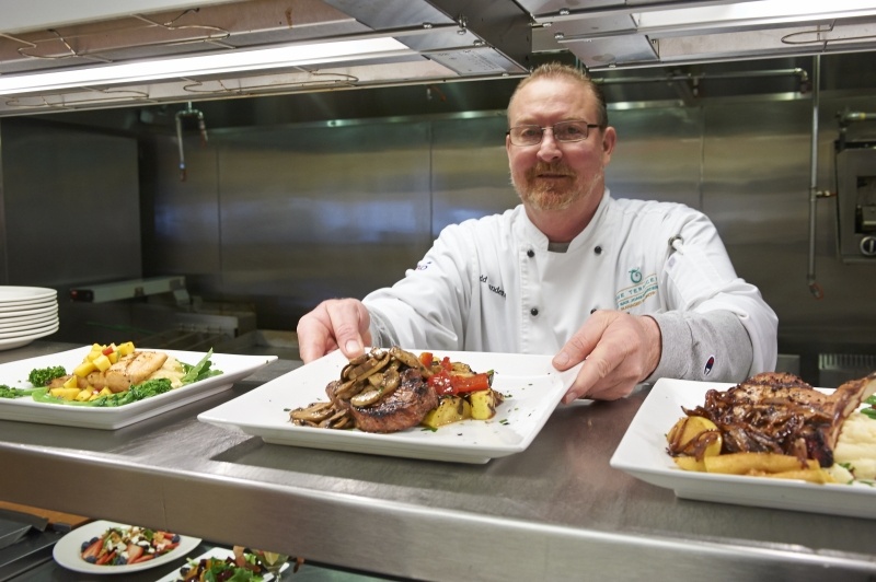 Chef placing dinner dish in the window of a restaurant kitchen