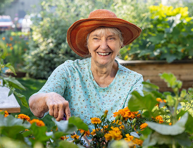 Senior woman in a sun hat gardening in a HumanGood Life Plan Community
