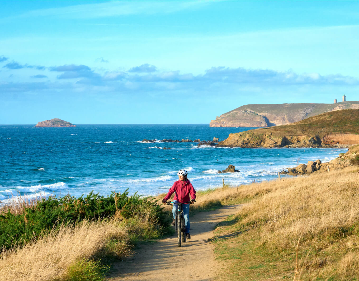 senior woman mountain biking on a path along the ocean