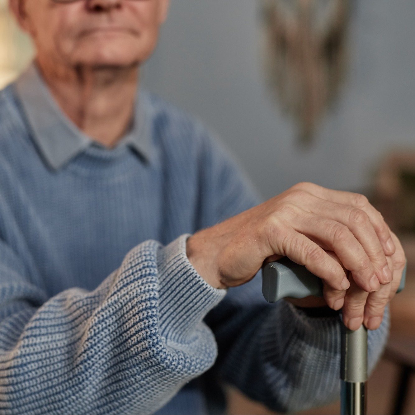 senior man leaning on cane in blue sweater