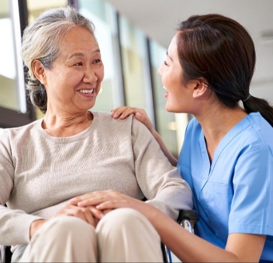 Nurse talking to a resident who is in a wheelchair.