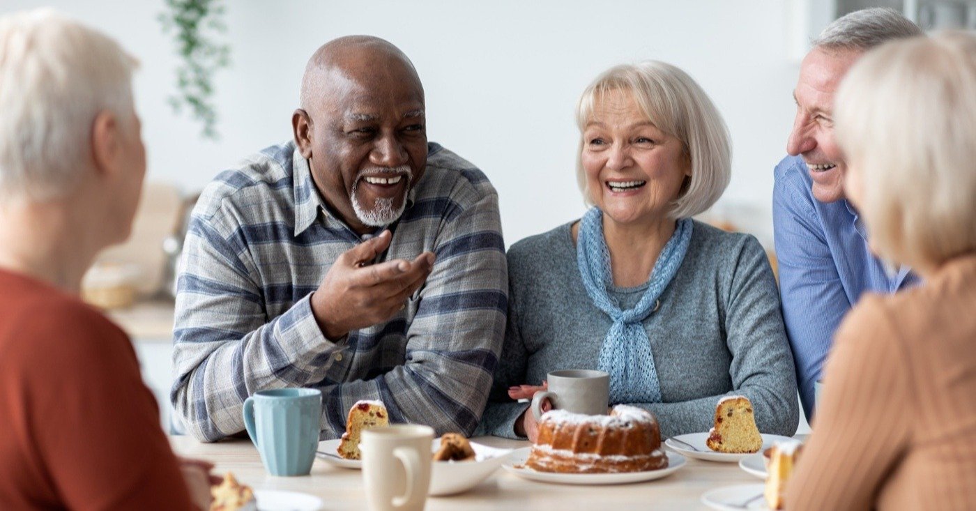 Group of positive elderly people drinking tea with cake