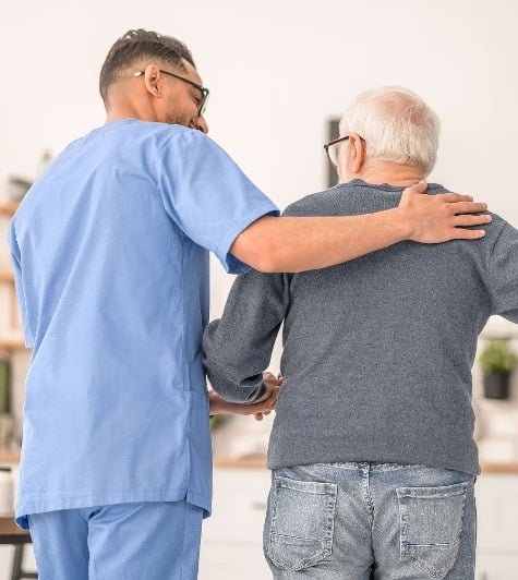 Medical worker assisting his patient to walk with a cane