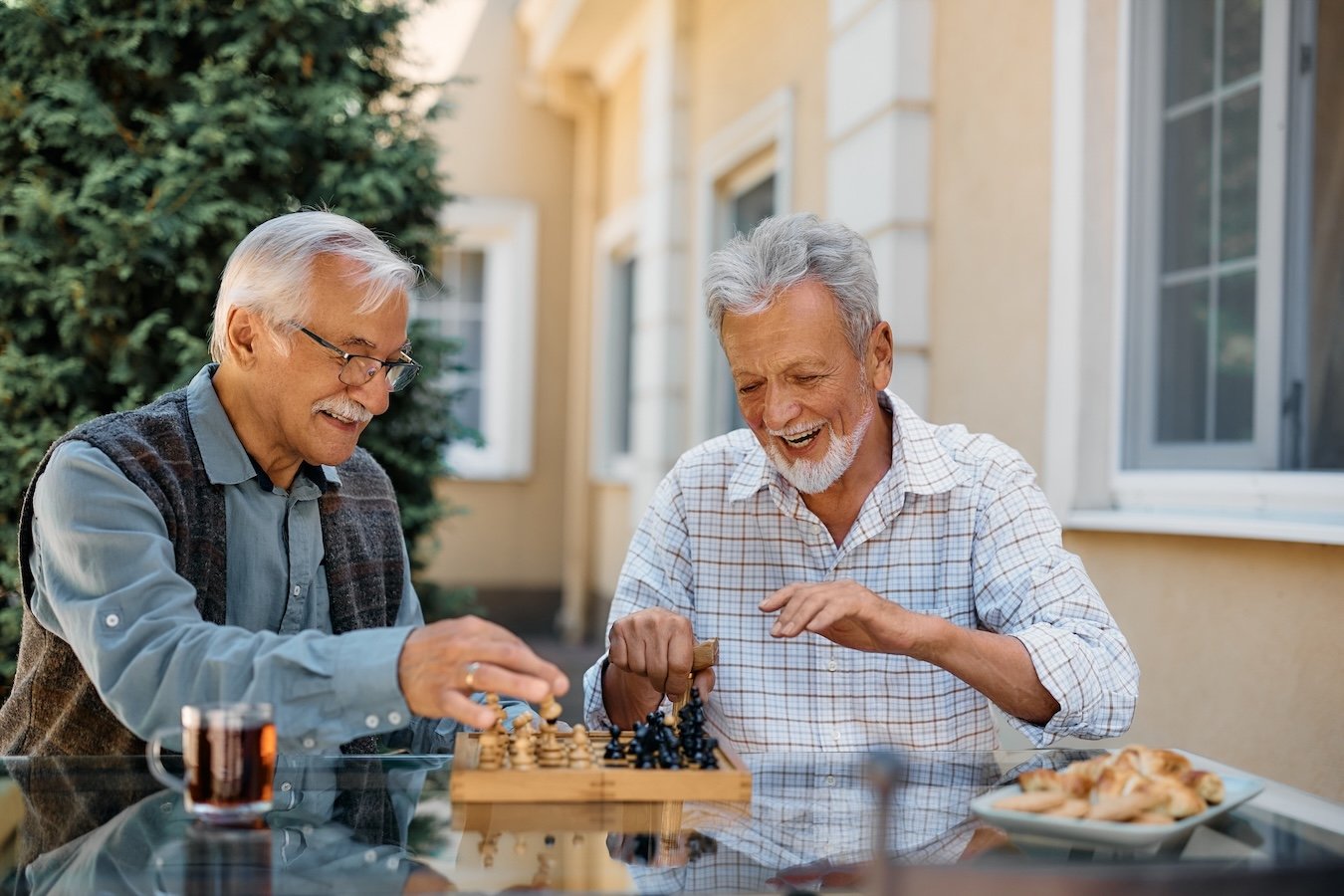 two senior men playing chess outside
