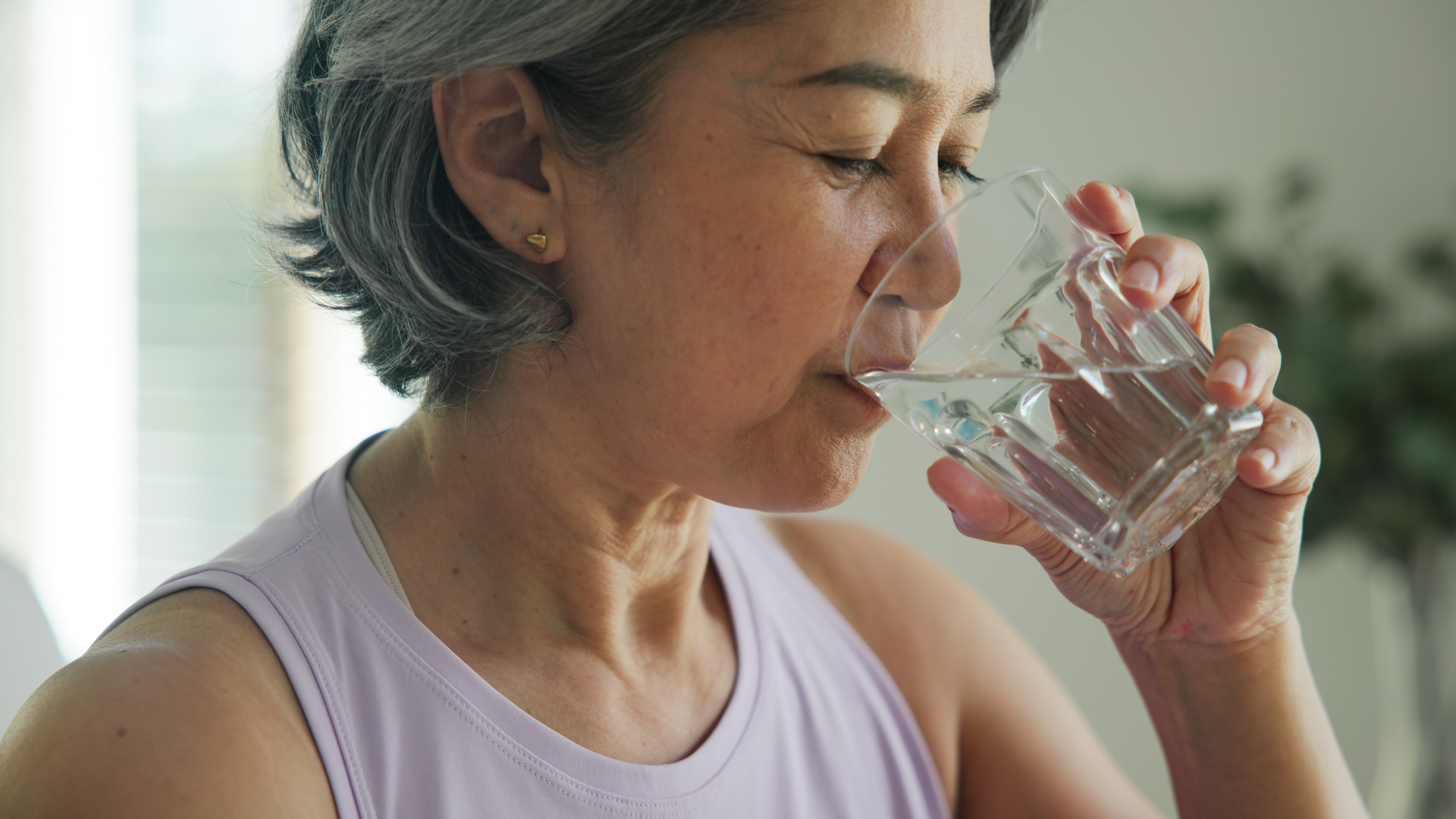 Close up senior woman sipping water from glass