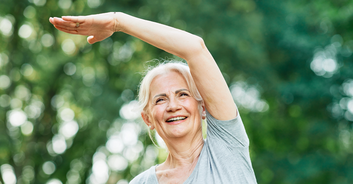 Woman smiling with arm raised against a blurred green background