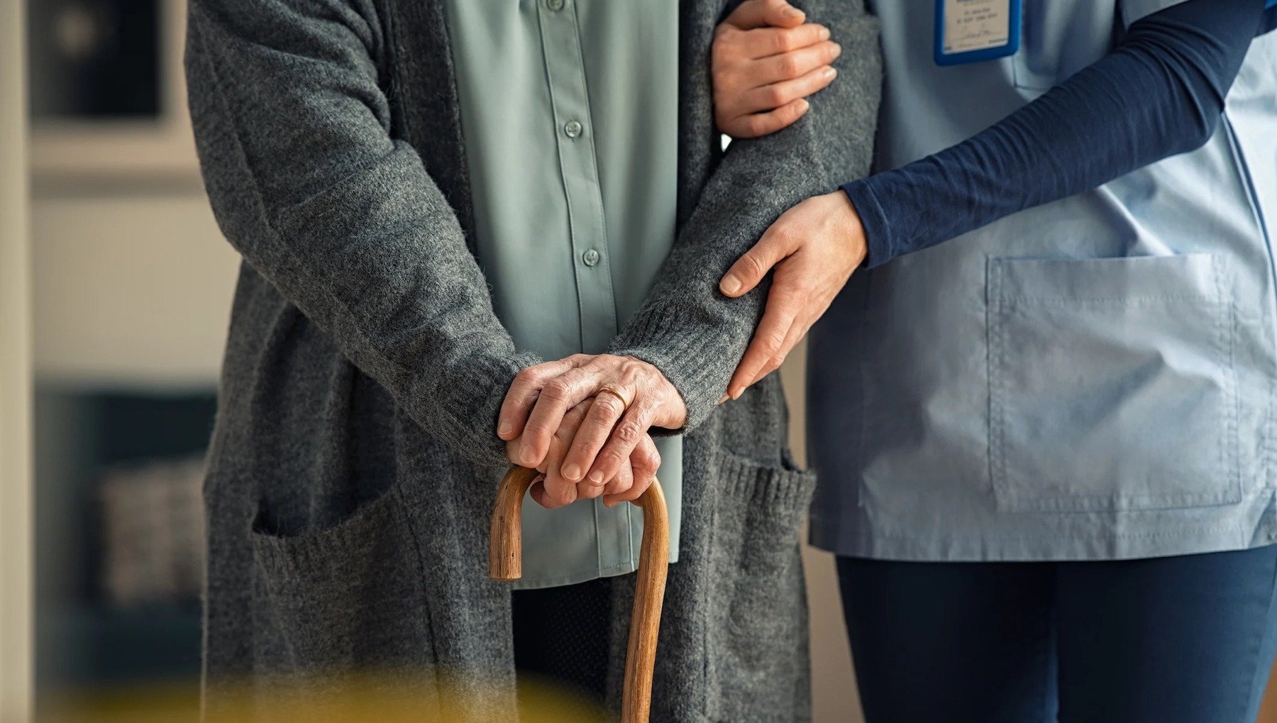 older woman with walker being assisted by a healthcare worker