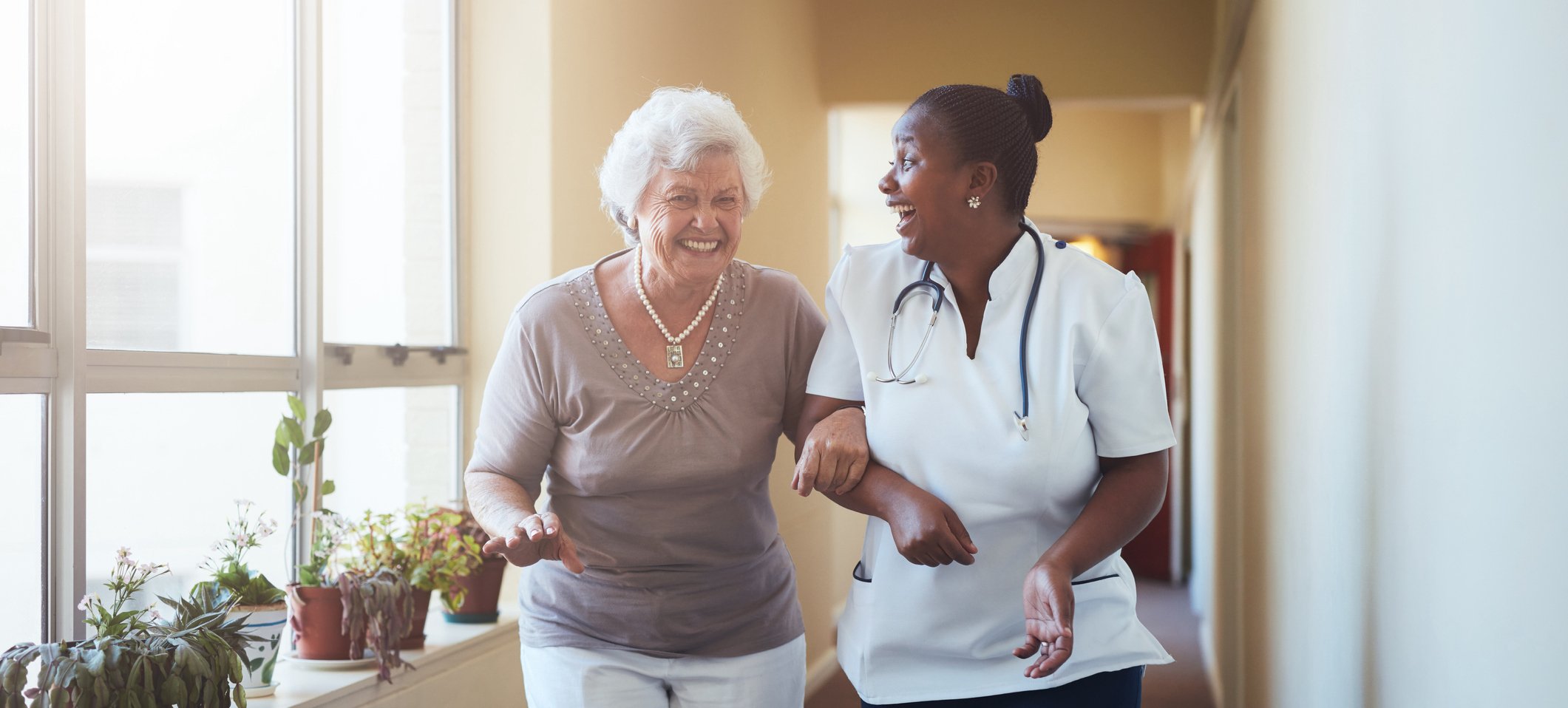 Senior woman and nurse holding arms