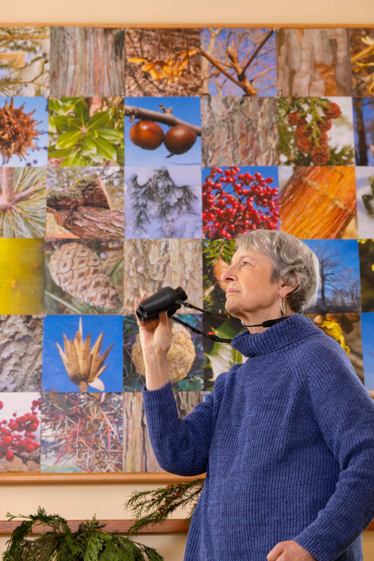Ann posing with binoculars in front of a nature background.