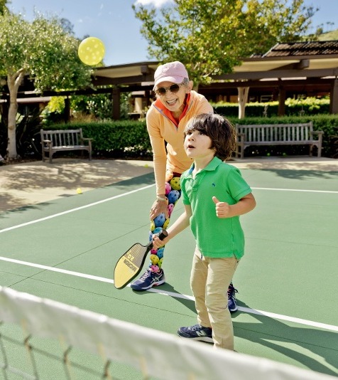 Grandmother playing pickle ball with her grandson