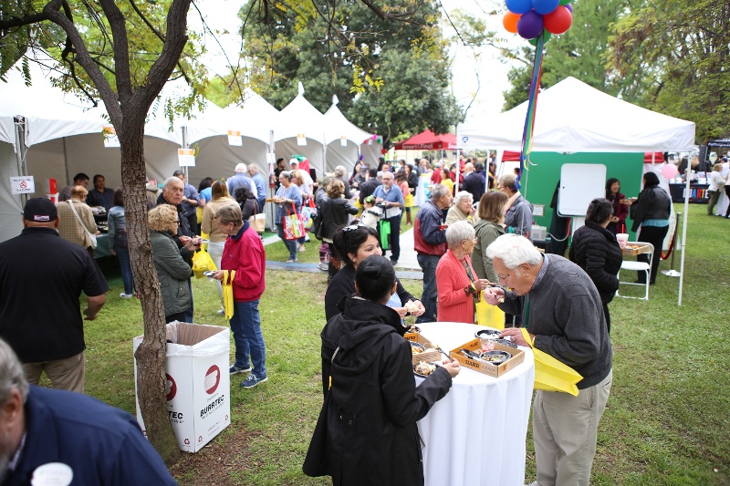 People eating food outside at a festival.